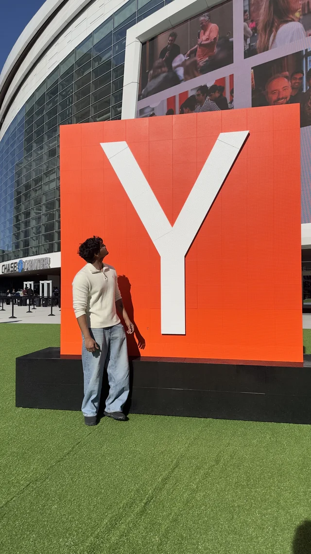 Tejas beside the Y Combinator sign